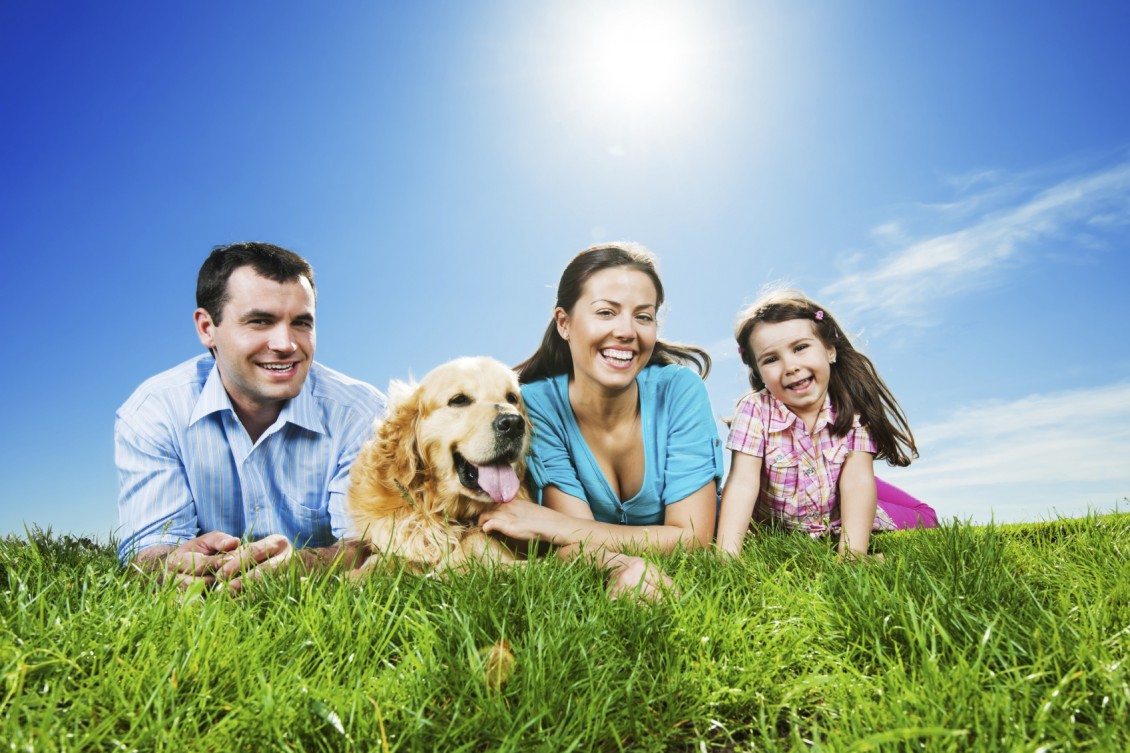 Happy family lying in the park with their dog.